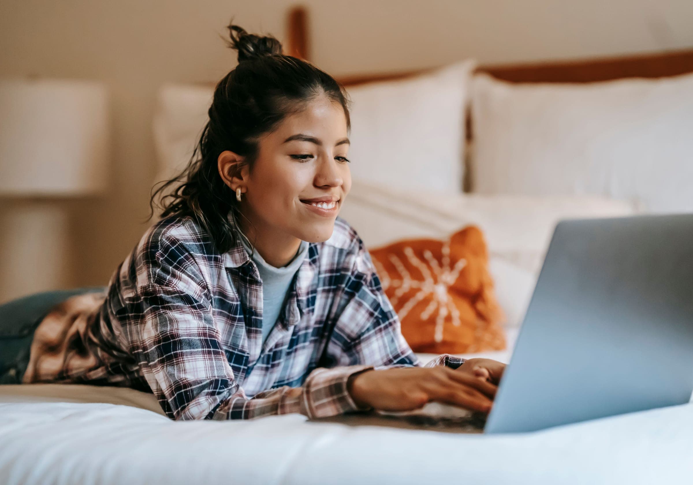 A woman smiling while using a laptop from home